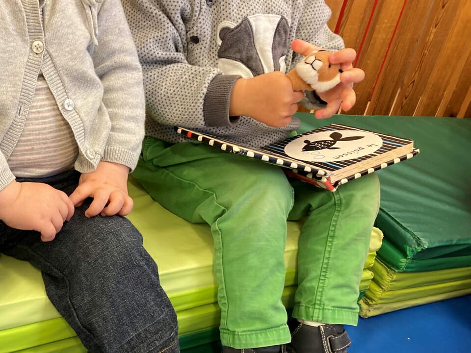 Bébé avec une peluche dans les mains et un livre sur les genoux