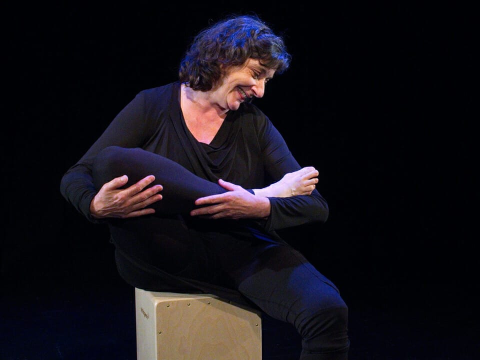 Une dame mime le maintien d'une nourrisson dans ses bras avec son pied
