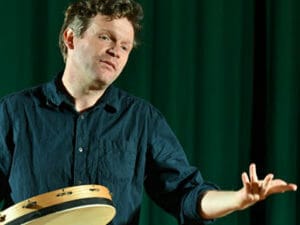 Conteur Matthieu Epp sur scène avec un tambourin